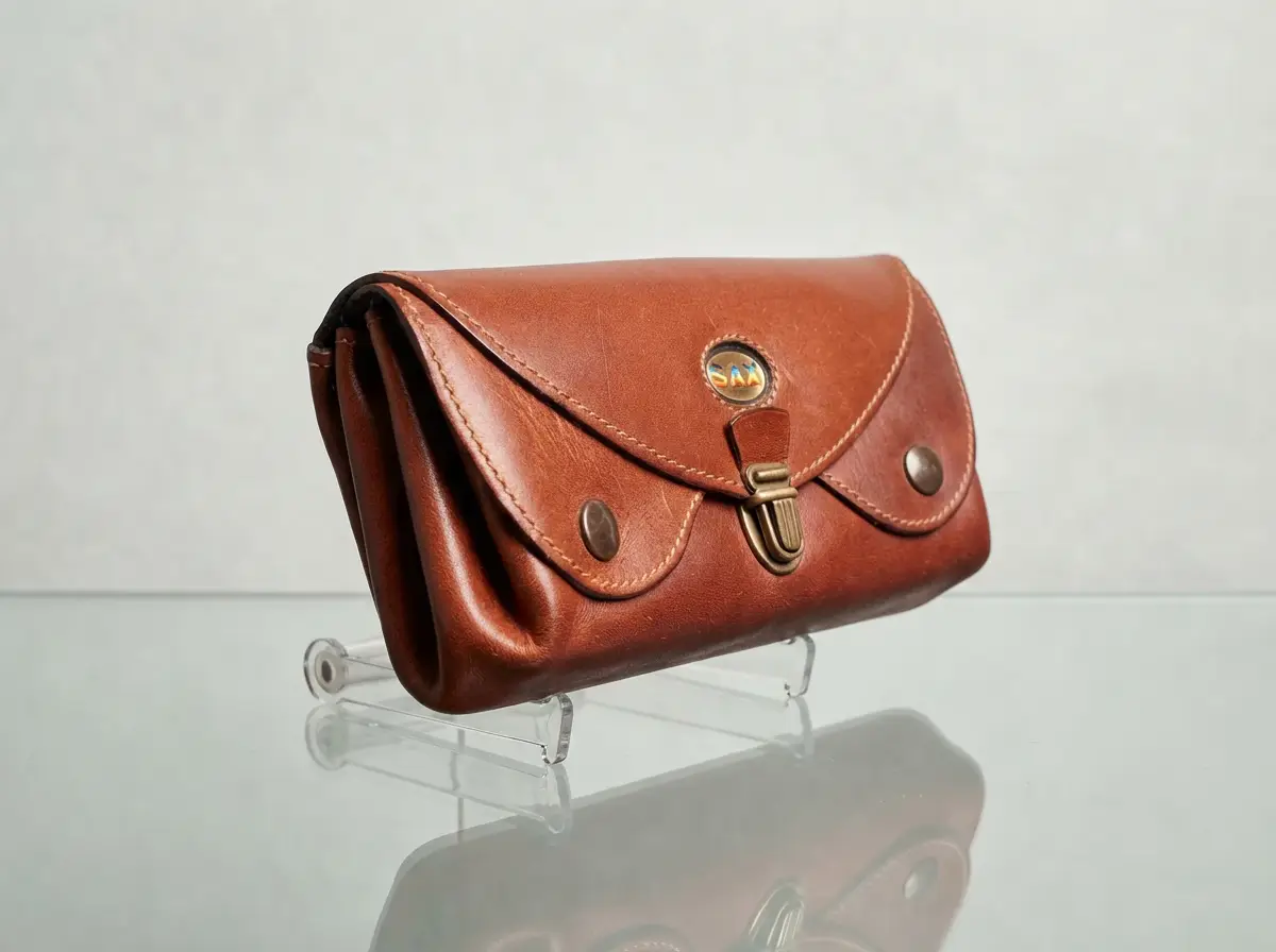 Braune SAX Ledergeldbörse im Vintage-Stil mit Metallverschluss auf einem Acrylständer vor neutralem Hintergrund