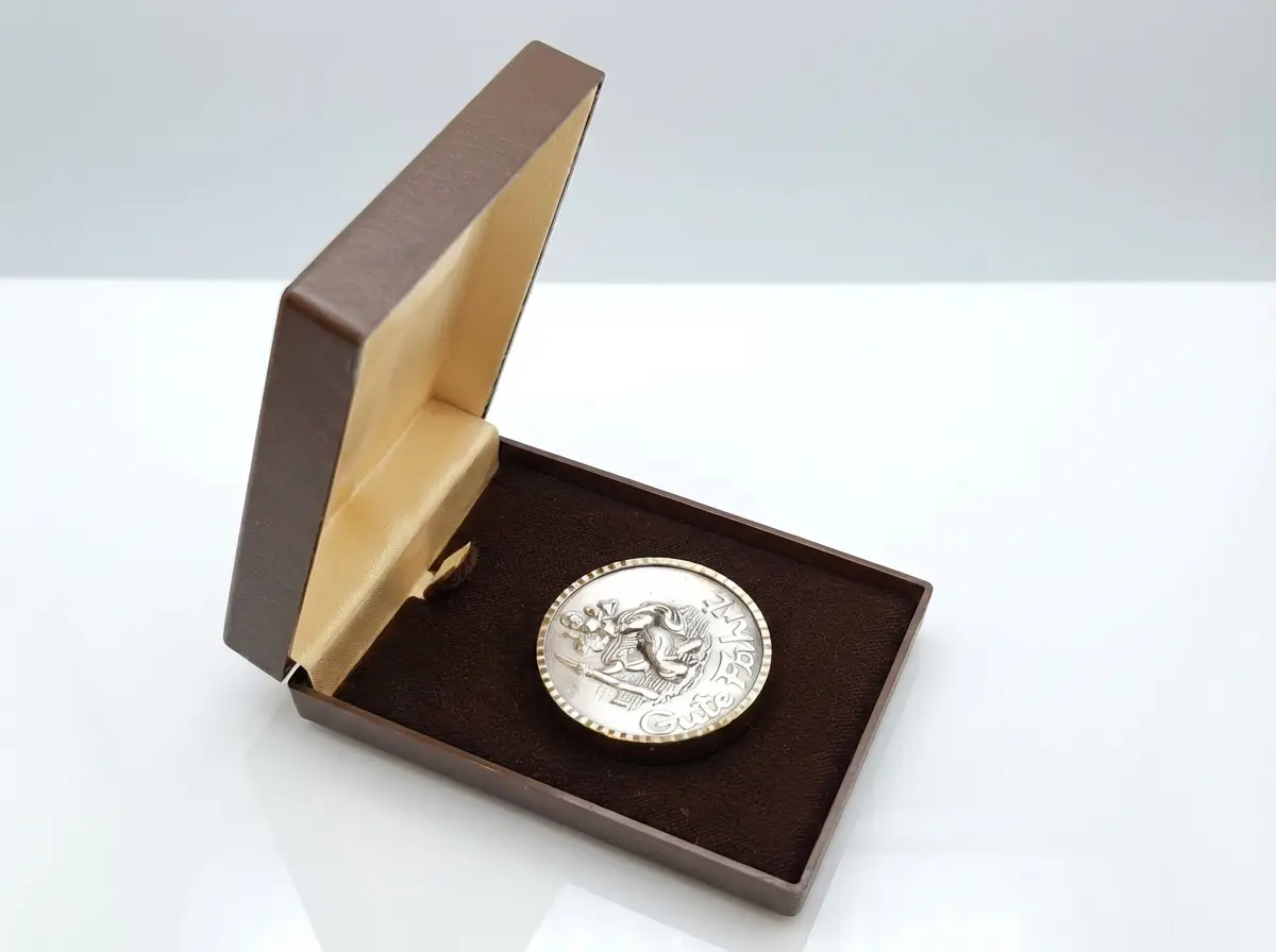 Silberne Christopherus-Plakette mit der Aufschrift Gute Fahrt und Motiv des Heiligen mit Kind in einer geöffneten braunen Schatulle