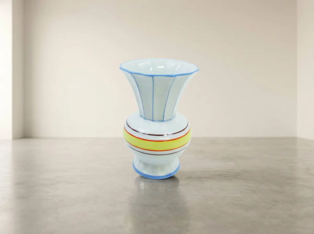 Kleine bauchige Porzellanvase im Vintage-Stil, weiß mit blauen vertikalen Linien am Hals und einem gelb-roten Querstreifen am Bauch.