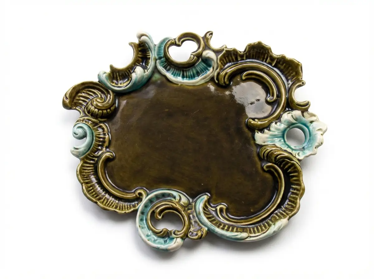 Dekorative glasierte Keramikplatte mit reliefartigen Jugendstil-Verzierungen in Olivgrün und Türkis vor weißem Hintergrund