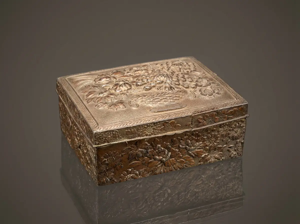 Rechteckige antike Silberdose mit geprägtem Blumenkorb-Motiv auf dem Deckel und üppigen floralen Ornamenten an den Seiten auf dunklem Untergrund