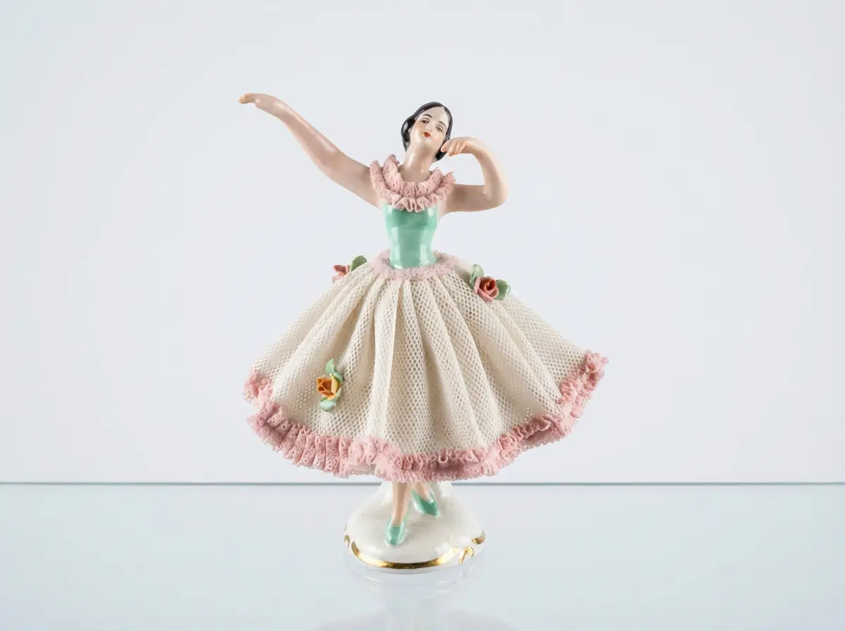 Porzellanfigur einer Tänzerin mit grünem Mieder und weißem Spitzenrock mit rosa Rüschen sowie Blumenverzierungen in einer Tanzpose