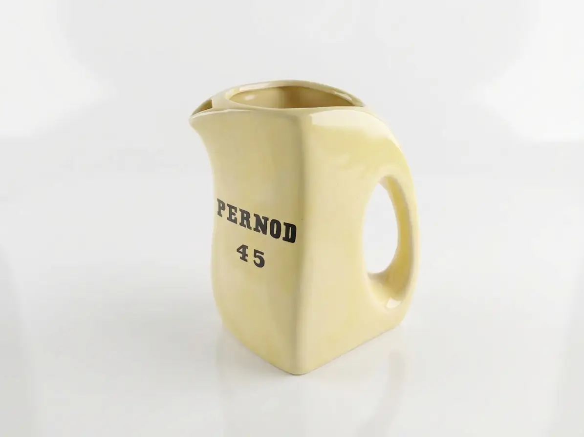 Cremefarbener Keramikkrug mit schwarzer Aufschrift 'PERNOD 45', weißer Hintergrund.