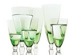 Gruppe verschiedener eleganter Trinkgläser mit grünem Farbverlauf am Boden auf weißem Hintergrund